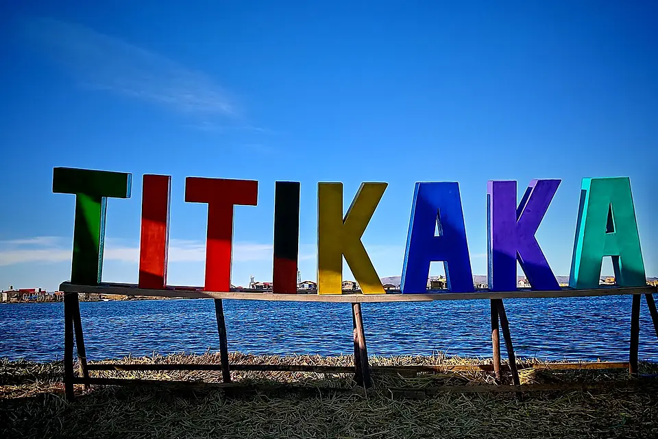 "TITIKAKA" a orillas del Lago Titicaca, con un cielo despejado y casas flotantes en el fondo. Es un símbolo representativo de la icónica Isla de los Urus